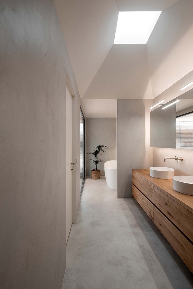 Vista del baño de la vivienda diseñada por Company Studio con mobiliario a medida y suelos de microcemento