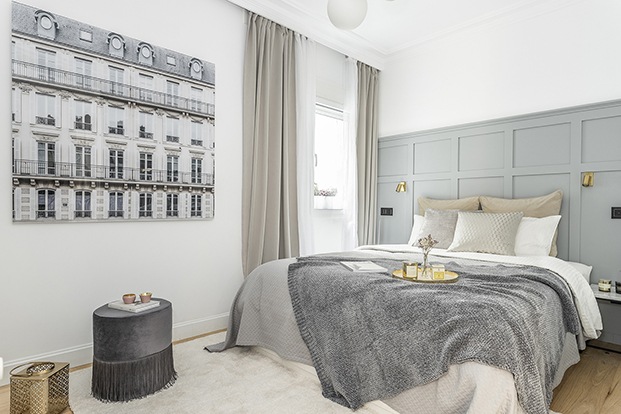 El dormitorio, con cabecero diseñado a medida, está vestido en tonos grises. La fotografía de París es de Guillaume Dutreix.