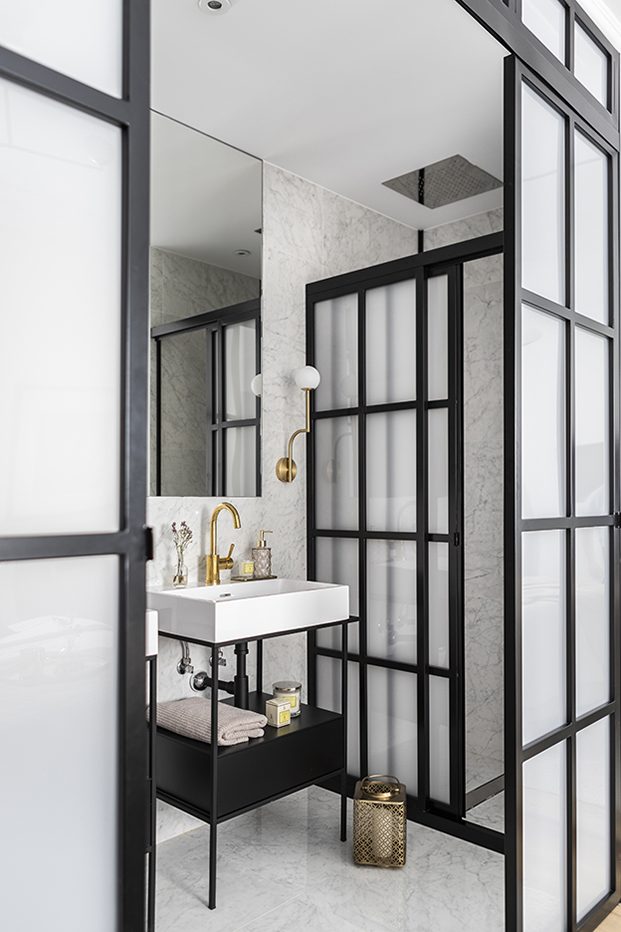 Detalle del cuarto de baño, delimitado con puertas de cristal y aluminio negro