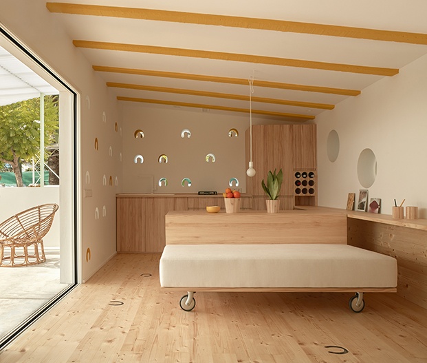 Un mueble de madera de pino recorre el perímetro de la casa y separa y delimita cada ambiente según el uso. 