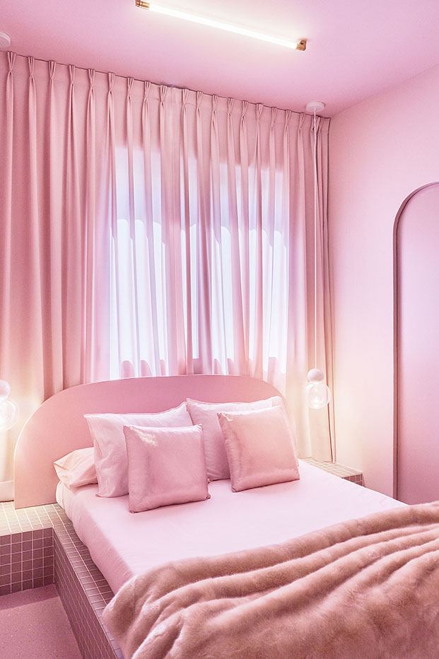 Cojines de lamé en rosa bebé  y mantas ecológicas en uno de los dormitorios, con cama de obra revestida de azulejos rosas