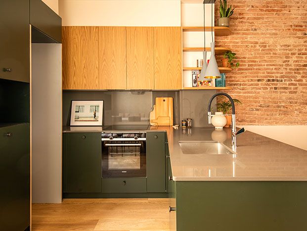La cocina se integra con la  textura y color, madera de roble para los muebles altos y lacado verde oscuro para los bajos