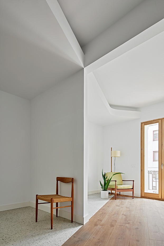 Un muro de carga separa dos de las habitaciones del piso del Ensanche barcelonés. La arquitectura juega con los volúmenes y contrastos en techos y suelos
