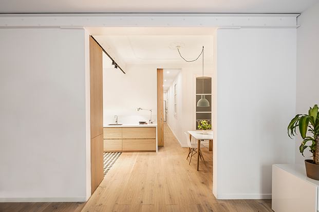 Desde el salón, vista de la cocina y el comedor, con la puerta corredera que lleva al dormitorio y el baño de este pequeño piso en Barcelona.