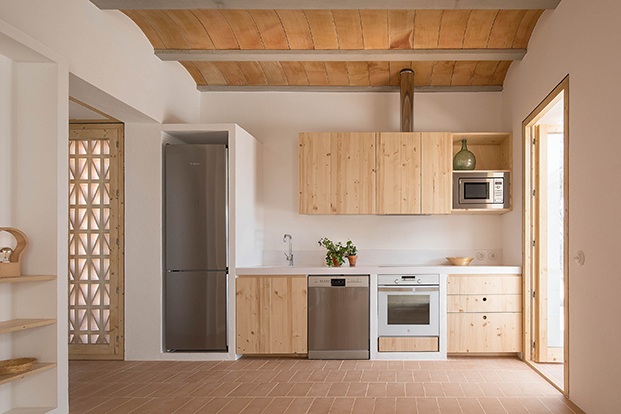 La cocina con mobiliario de madera, y encimera de Corian. El techo de bovedilla mallorquin y el suelo de baldosas de terracota prensada