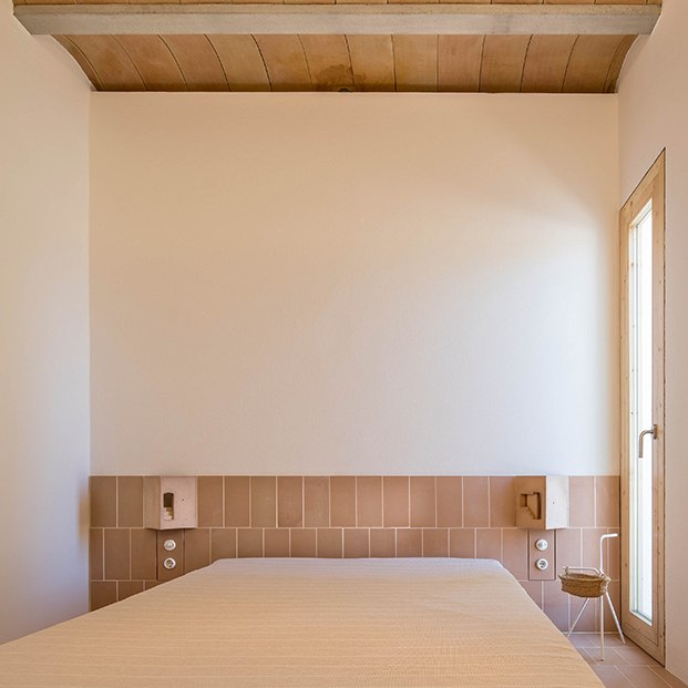 En el el dormitorio se ha realizado un cabecero de obra con baldosas cerámicas y luminarias, diseño de Marià Castelló integradas