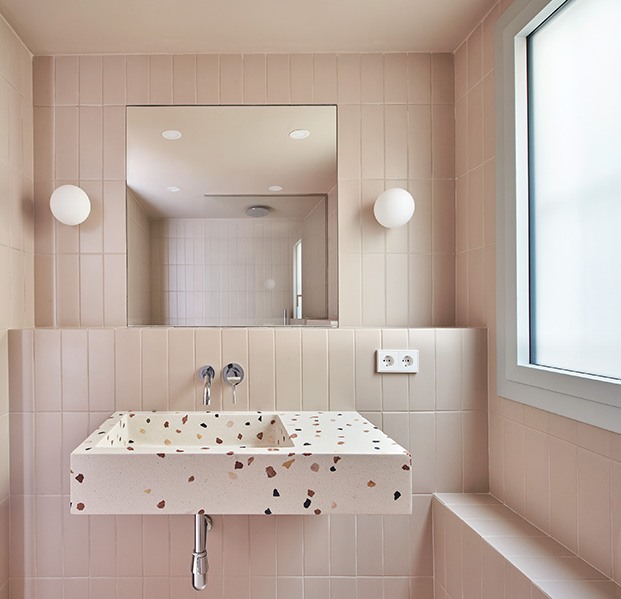 El cuarto de baño con un lavamanos de Huguet Mallorca con estampado de terrazo. Las baldosas se han escogido a tono con los armarios