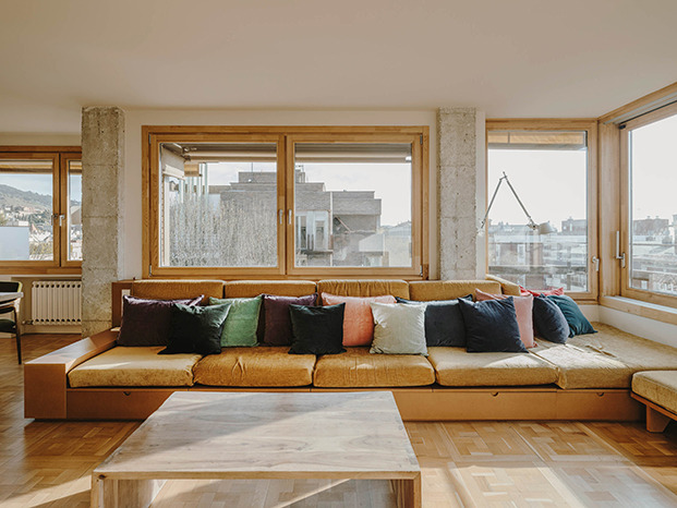 El sofá, realizado a medida permite ampliar su espacio con módulos y pufs. Las mesas son de hormigón hechas a medida