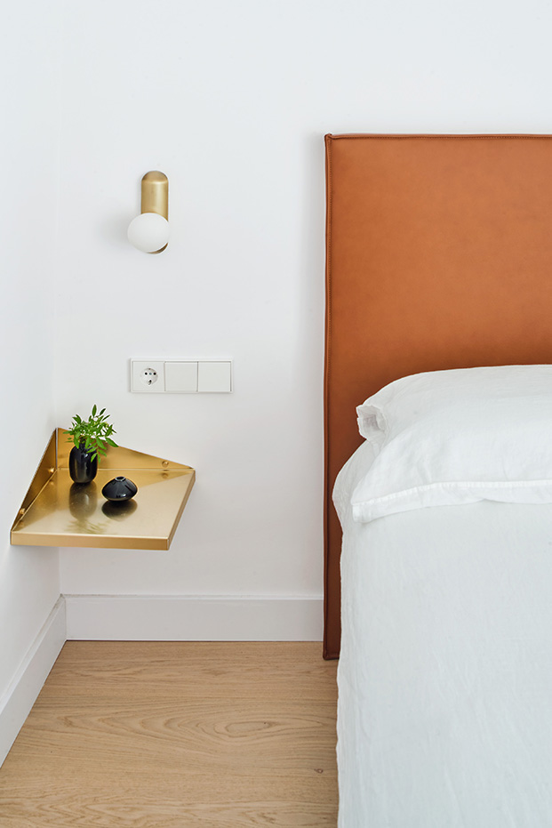 Dormitorio principal con la cama con un cabecero de piel natural de RSA y mesillas de latón diseño de la misma firma, las lámparas de latón son de Metalware
