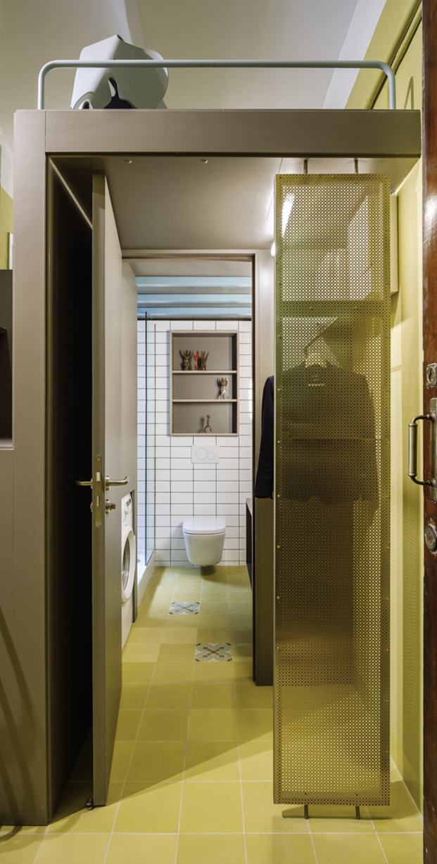 El baño, una zona de armarios y el altillo en el techo con una silla Elephant Eames de Vitra en este apartamento de 60 m2 en Barcelona