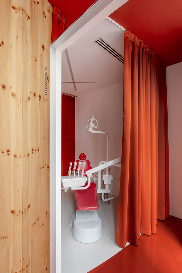 Impress clínica dental en Milán diseñada por Raúl Sánchez Architects. Cortinas rojas. Madera curvada