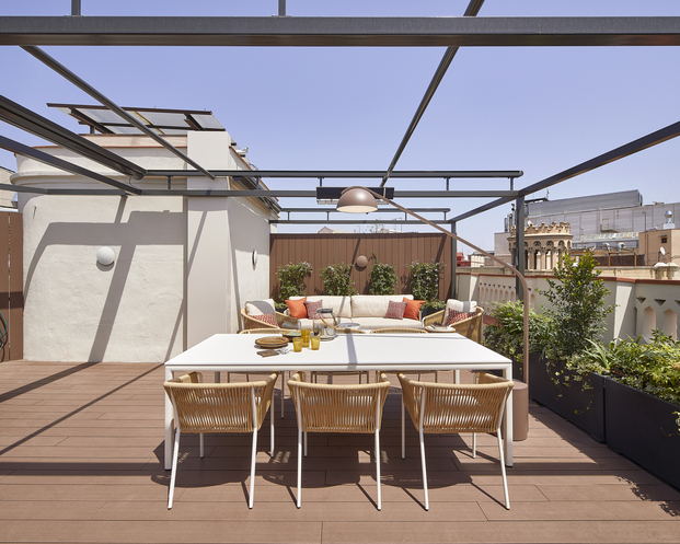 El salón comedor de esta terraza, diseñada por Molins Design, cuenta con una estructura metálica que alberga tres toldos enrollables