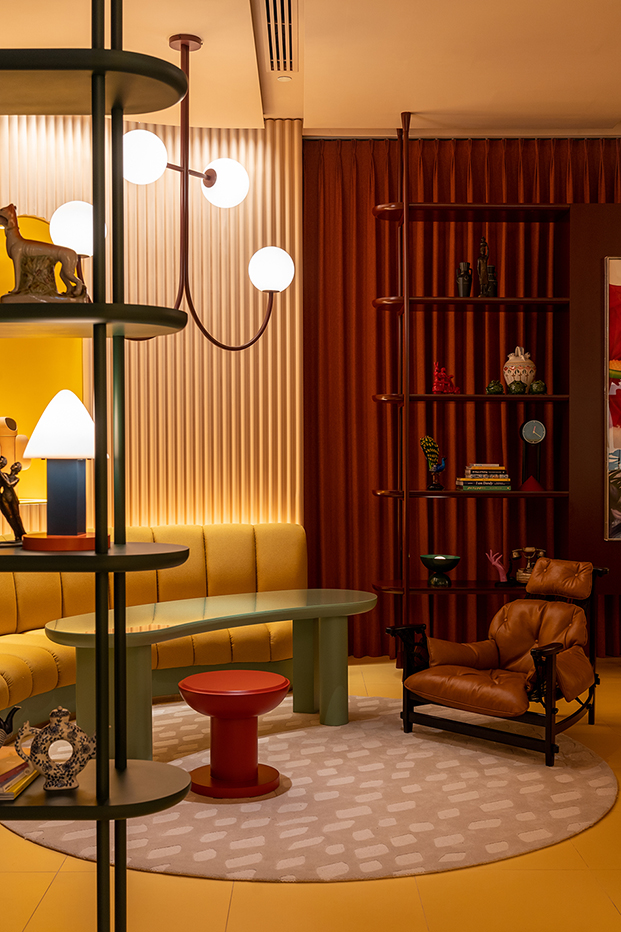 sofá amarillo y pared roja con textura, mesa verde, sillón Sergio Rodrigues