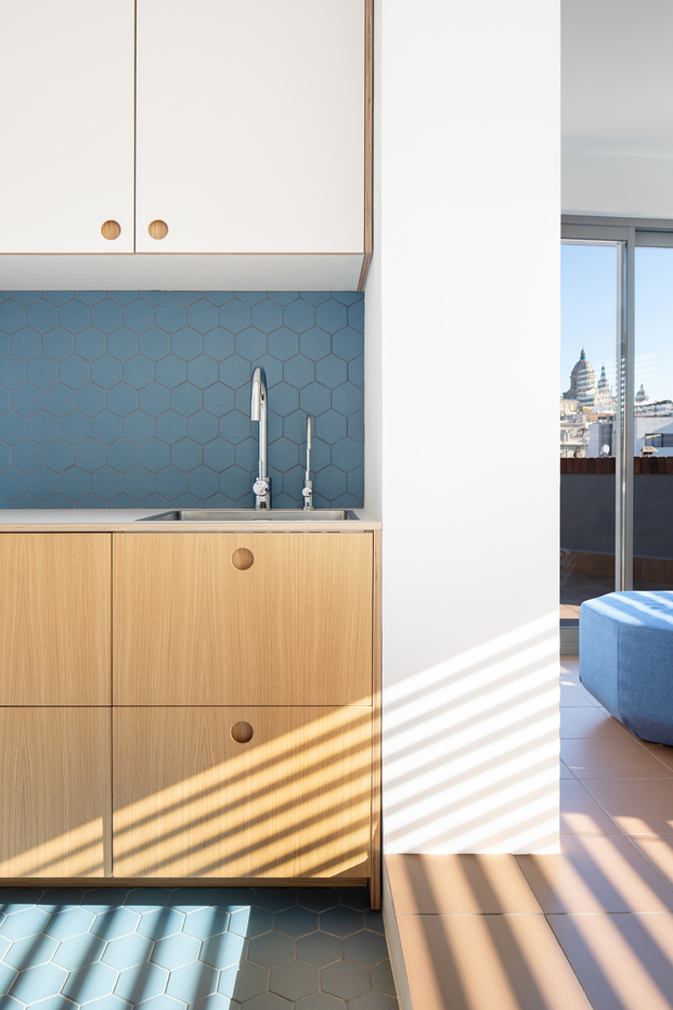 Muebles de roble y delimitación espacial gracias al pavimento cerámico de color azul.