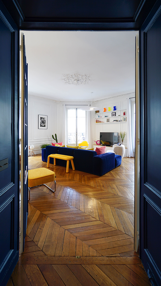 salón con sofá azul eléctrico. suelo en espiga, salón triangular, paredes con molduras