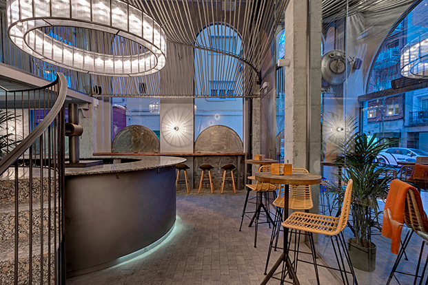 interior de bar con barra circular, lámpara circular, pilares de hormigón visto