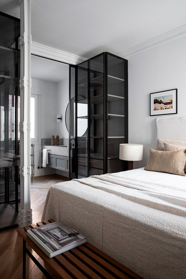 dormitorio con armarios negros de cristal y banco de madera