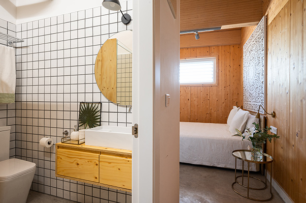 casa eficiente, casa bajo consumo energético, baño con azulejos blancos y rayas negras, paredes de madera