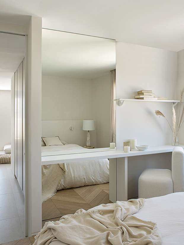 dormitorio en tonos blancos con espejo en pared