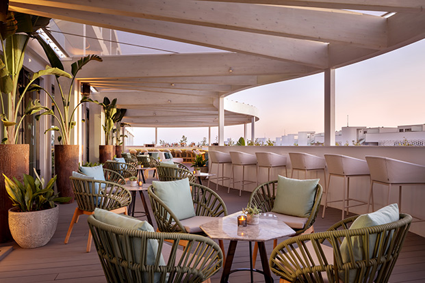 terraza de hotel con puesta de sol, sillas de mimbre