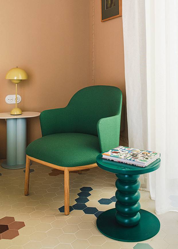 sillón verde, mesita circular verde y paredes naranjas