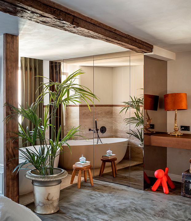 baño de diseño con vigas y bañera y paredes de espejo